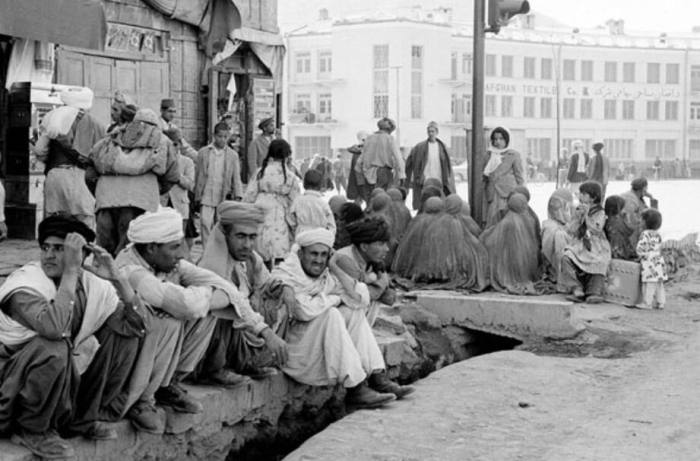 زنان برقع پوش و مردان در حاشیه یکی از میادین شهر کابل؛ چراغ راهنمایی و رانندگی در این تصویر دیده می شود. ۱۹۶۴